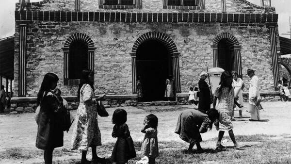 Women and children in front of a mission church, black and white photo.