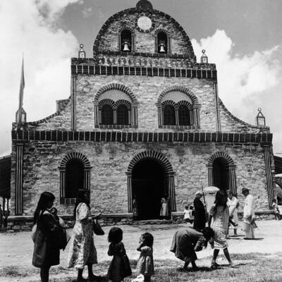 Women and children in front of a mission church, black and white photo.
