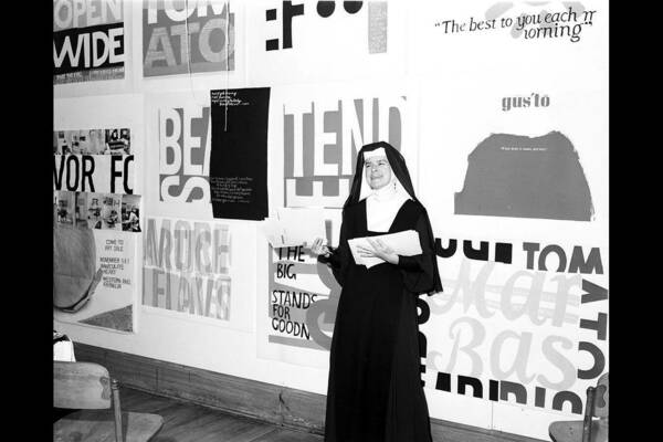 Sister Corita in front of her art.