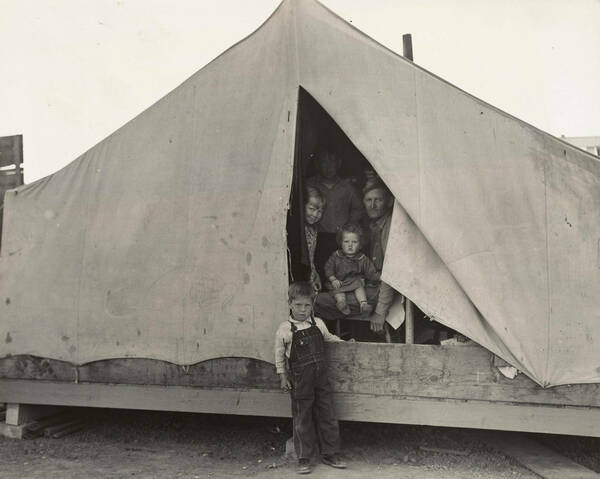 Depression era family members in a migration camp tent.