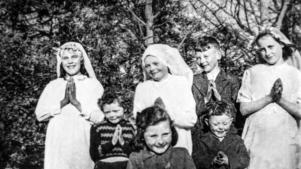 Seven children pose prayerfully for a photo