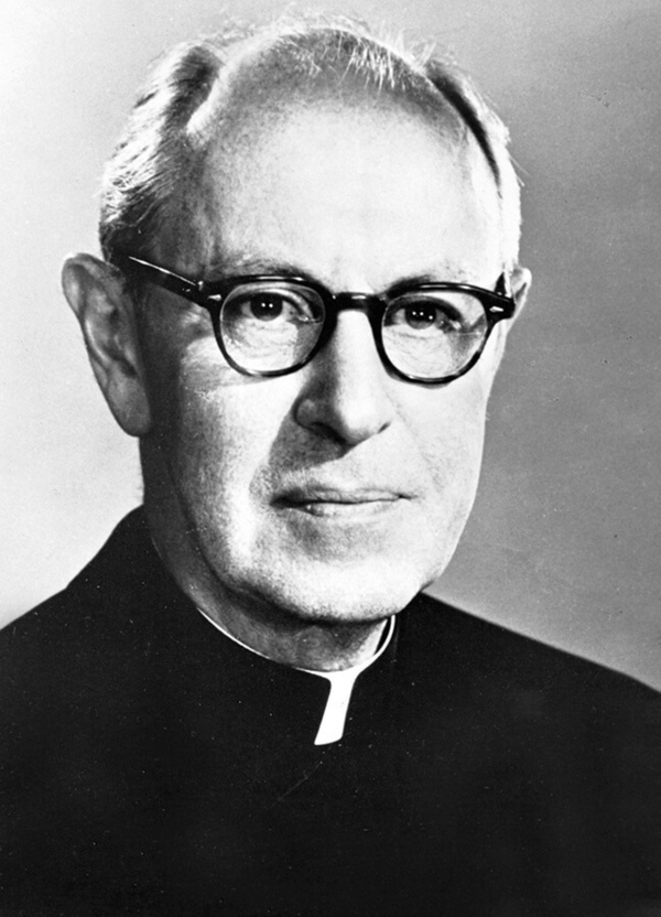 Black and white headshot of a priest wearing glasses and a clerical collar.